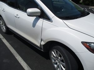 dent to door and surrounding area of a white SUV