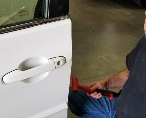 Technician at Collision Center of Andover handling a paintless dent repair to a white vehicle. We are a full service auto repair shop serving the Wichita area.