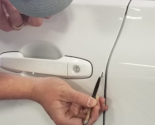 Technician at Collision Center of Andover handling a paintless dent repair to a white vehicle. We are a full service auto repair shop serving the Wichita area.