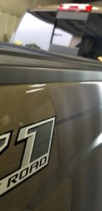 Collision Center of Andover technician working on an auto body repair to handle paintless dent repair on a gold truck.